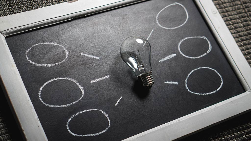 Lightbulb on chalkboard with idea bubbles